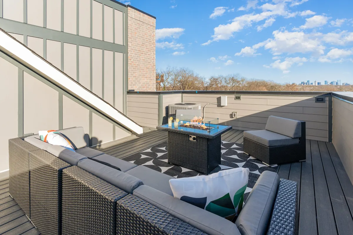 This image presents an elegant rooftop lounge area with comfortable seating and a decorative coffee table, set against the backdrop of Nashville's city skyline. The view emphasizes the exclusivity and stunning vistas available from the rooftops.